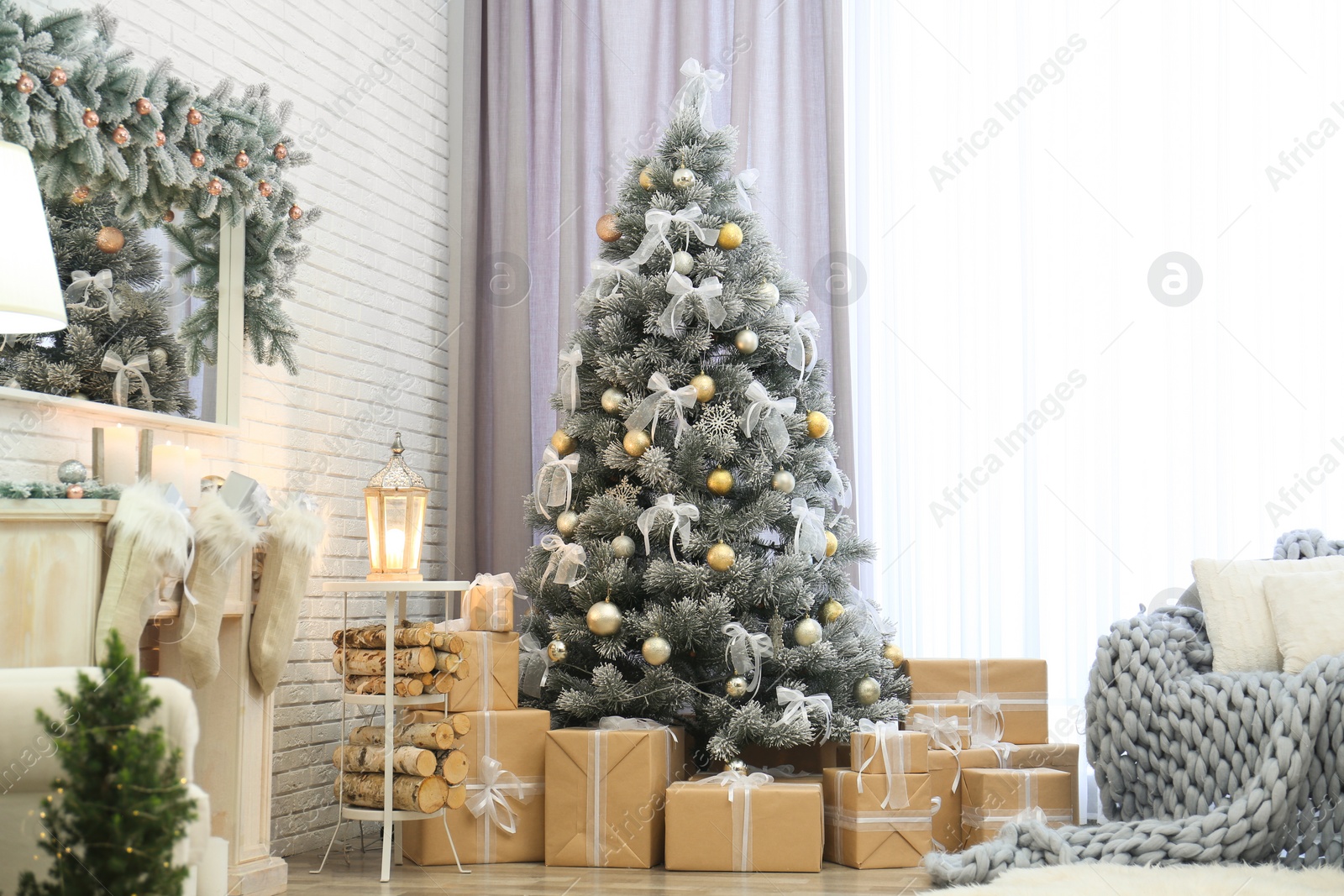 Photo of Decorated Christmas tree with gifts near window in room