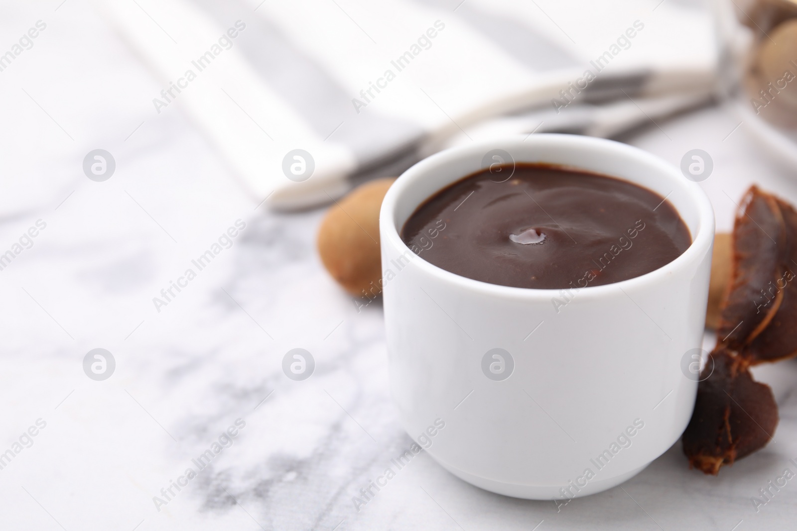 Bowl of tamarind sauce and fresh pods on white marble table. Space for text Photo of Bowl of tamarind sauce and fresh pods on white marble table. Space for text