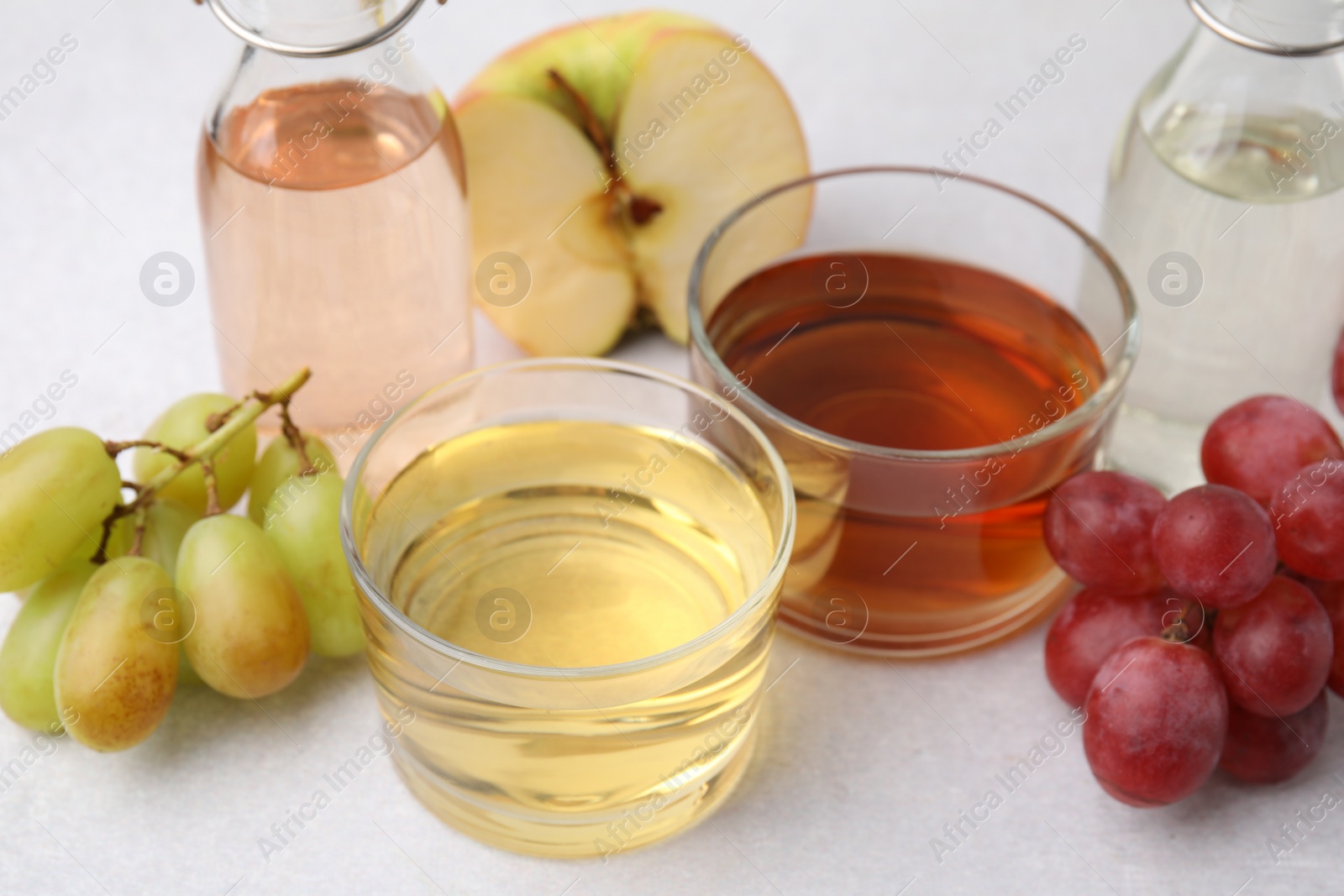 Photo of Different types of vinegar and ingredients on light table, closeup