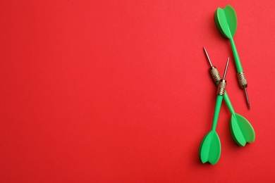 Photo of Green dart arrows on red background, flat lay with space for text