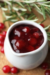 Photo of Cranberry sauce in pitcher, fresh berries and rosemary on board, closeup