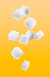 Refined sugar cubes in air on orange background