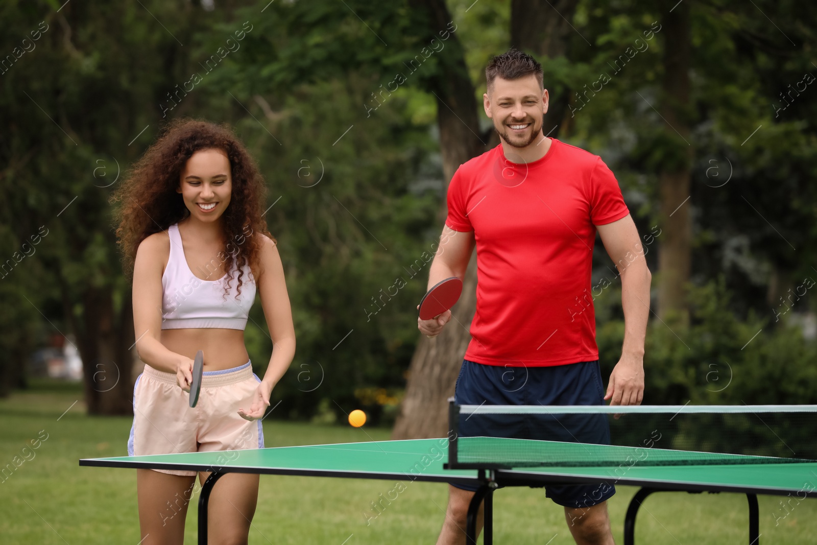 Photo of Friends playing ping pong outdoors on summer day