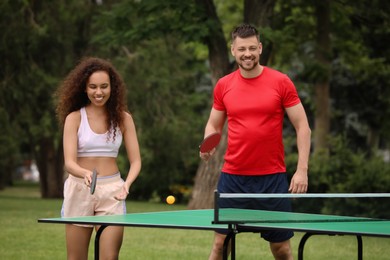 Friends playing ping pong outdoors on summer day