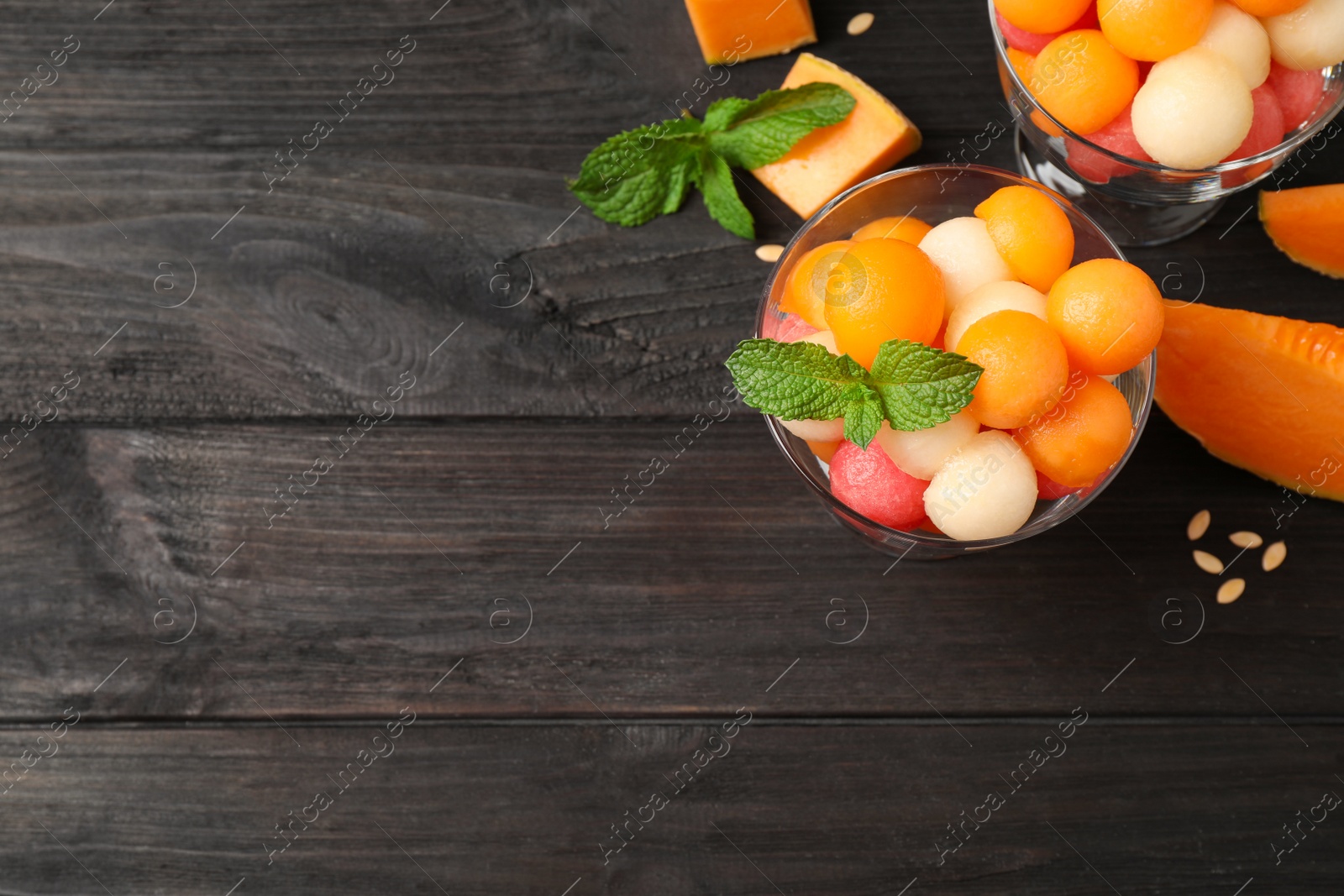 Photo of Melon and watermelon balls on black wooden table, flat lay. Space for text