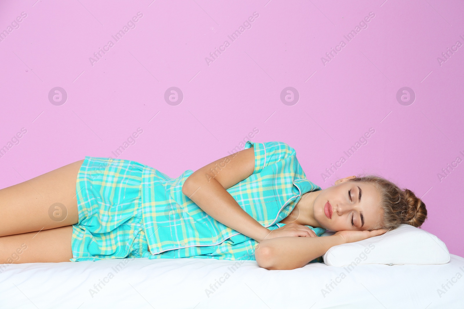 Photo of Beautiful woman sleeping with orthopedic pillow on bed against color background