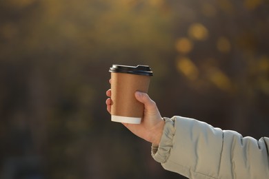 Photo of Woman with takeaway coffee cup outdoors, closeup