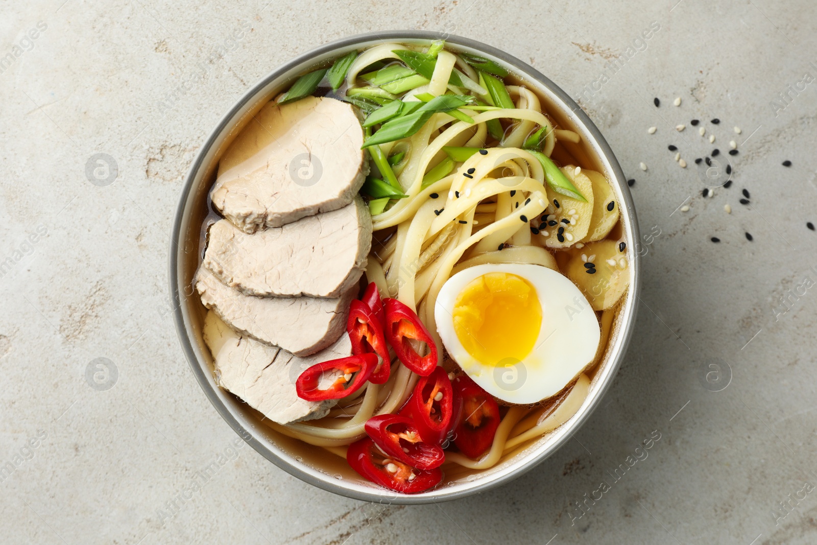 Photo of Delicious ramen in bowl on light textured table, top view. Noodle soup