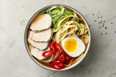 Photo of Delicious ramen in bowl on light textured table, top view. Noodle soup