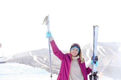 Happy young woman with ski equipment spending winter vacation in mountains