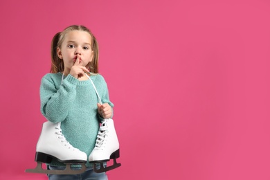 Photo of Cute little girl in turquoise knitted sweater with skates on pink background, space for text