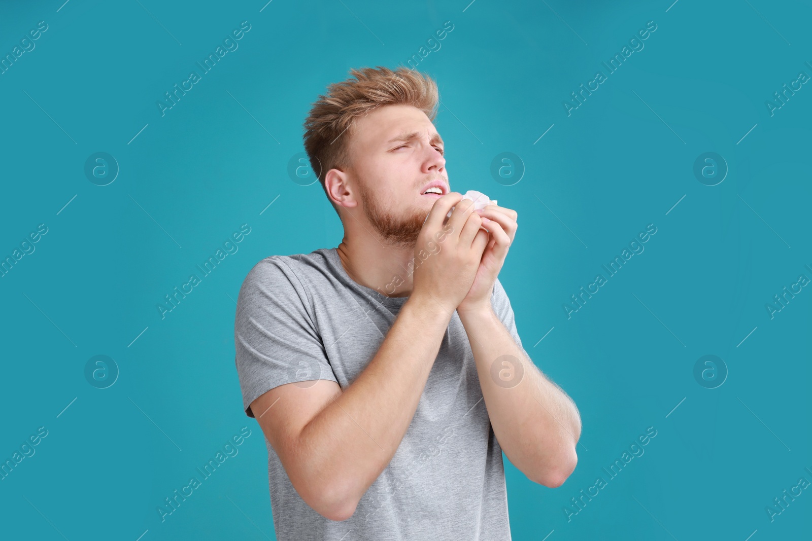 Photo of Young man suffering from allergy on blue background