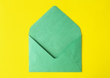 Photo of Green paper envelope on yellow background, top view