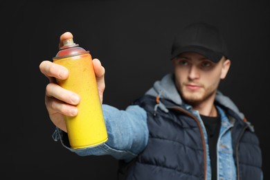 Handsome man holding used spray paint against black background
