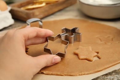 Photo of Woman holding cookie cutter at table, closeup. Christmas biscuits