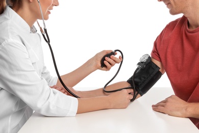 Doctor checking patient's blood pressure against white background, closeup. Cardiology concept