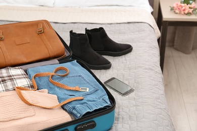 Photo of Suitcase packed for trip on bed in room