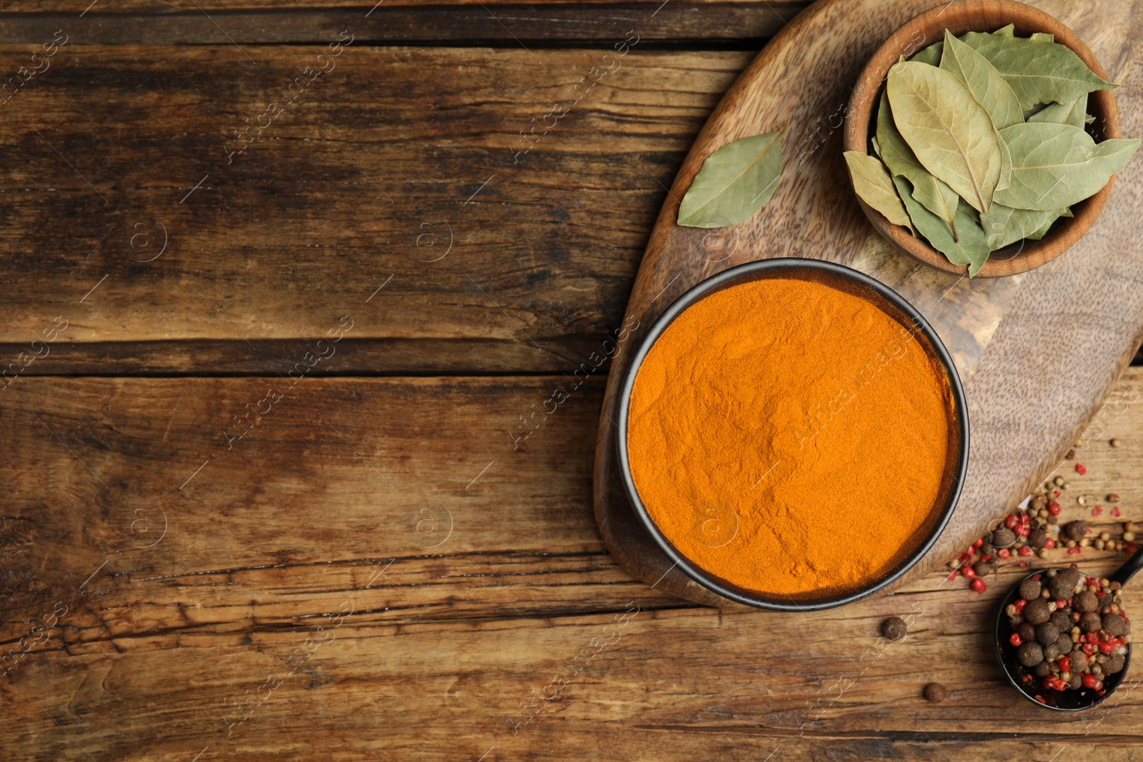 Photo of Bowl with saffron powder, peppercorns and bay leaves on wooden table, flat lay. Space for text