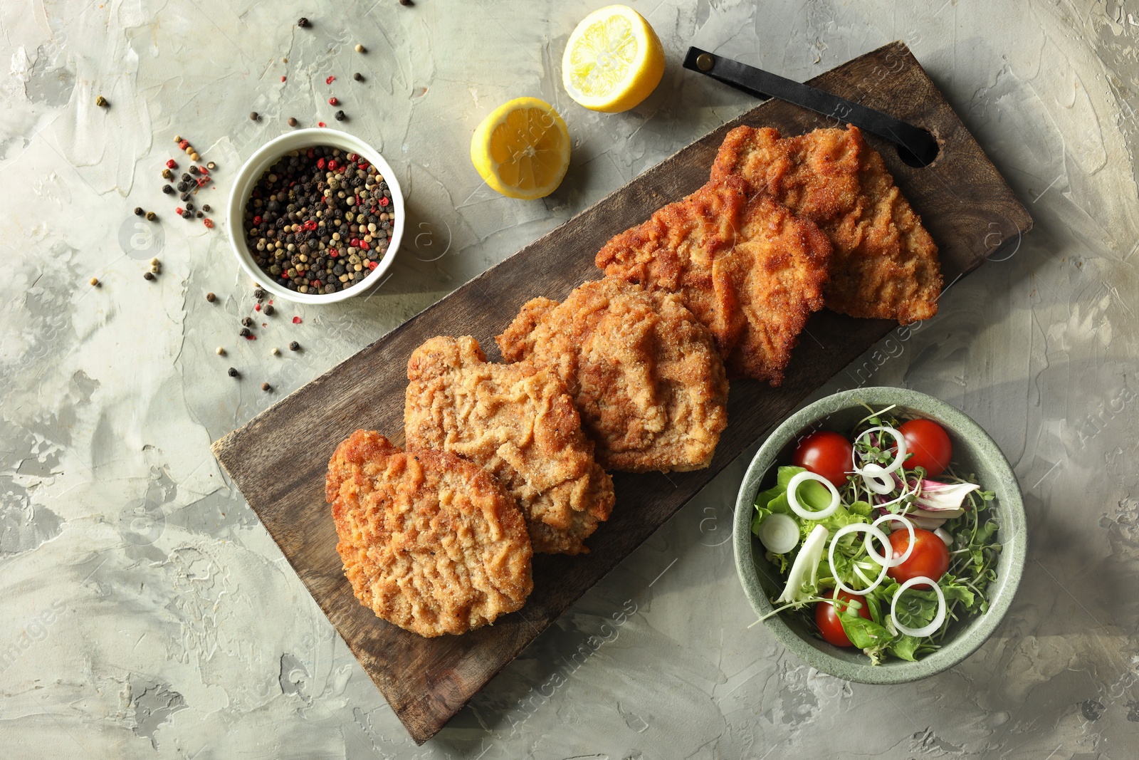 Photo of Tasty schnitzels served with lemon and salad on grey table, flat lay