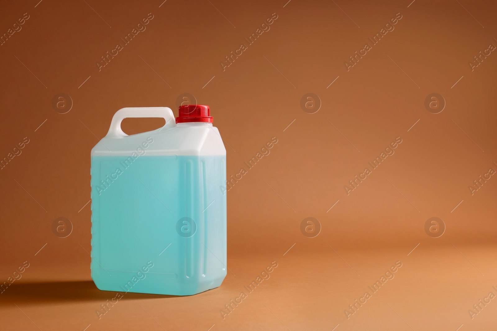 Photo of Plastic canister with blue liquid on brown background. Space for text