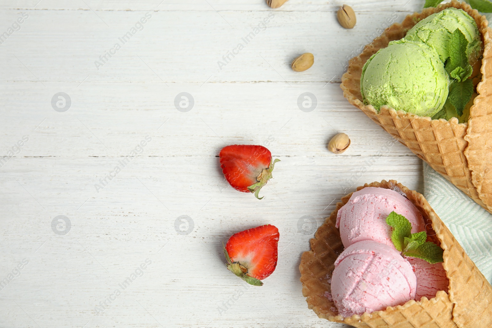 Photo of Flat lay composition with delicious ice creams in waffle cones on wooden table, space for text