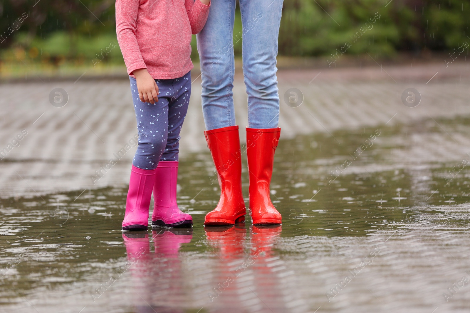 Photo of Mother and daughter wearing rubber boots on street, closeup