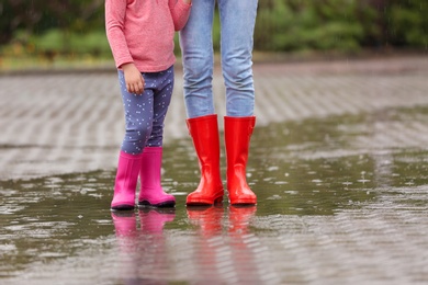 Mother and daughter wearing rubber boots on street, closeup