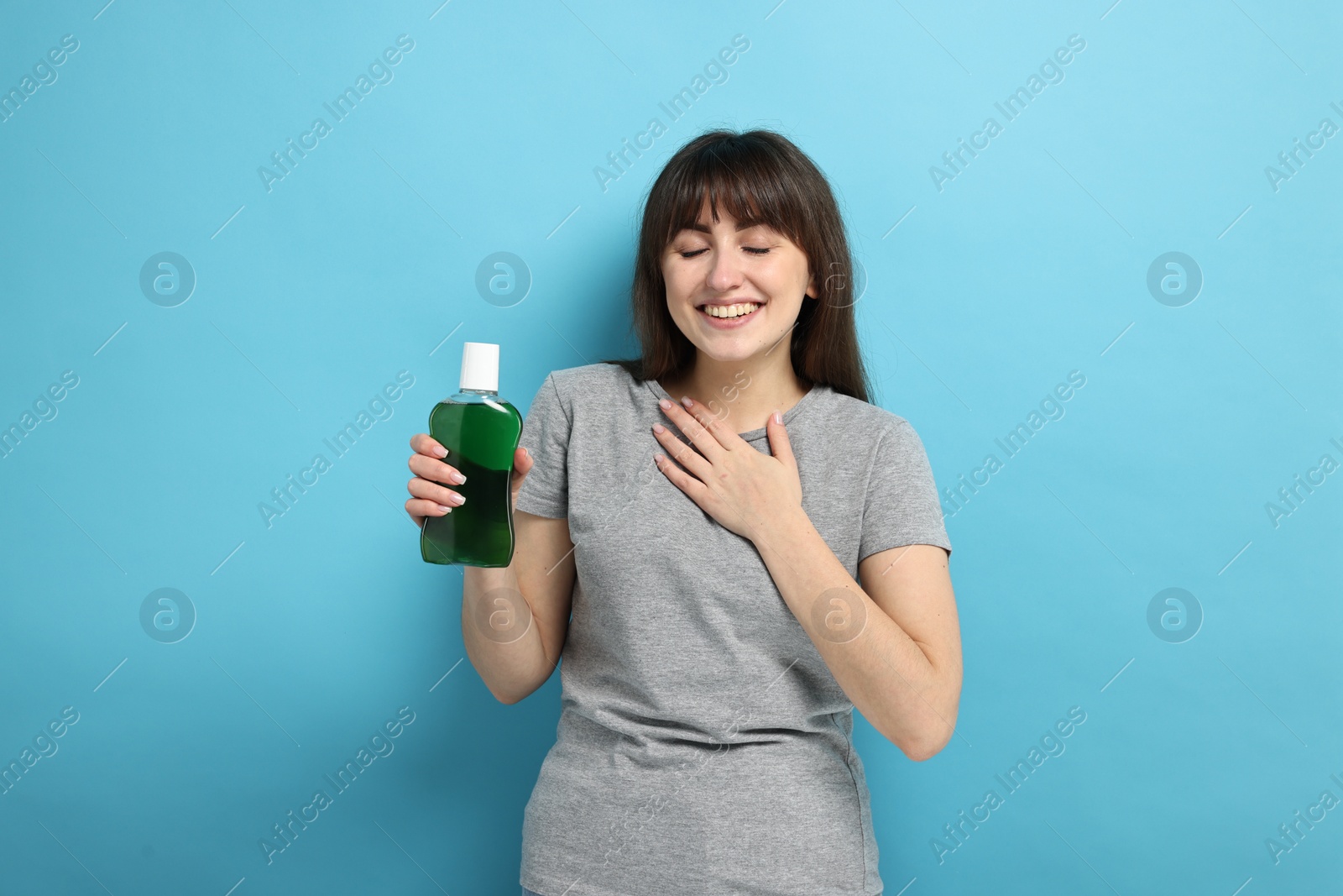 Photo of Young woman with mouthwash on light blue background