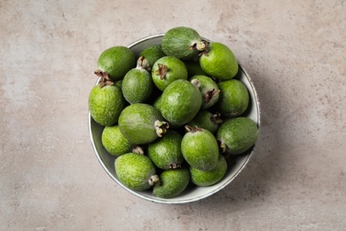 Fresh green feijoa fruits in bowl on light grey table, top view