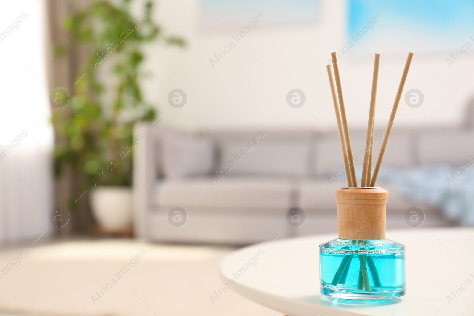 Photo of Reed air freshener with essential oil on table in room. Space for text