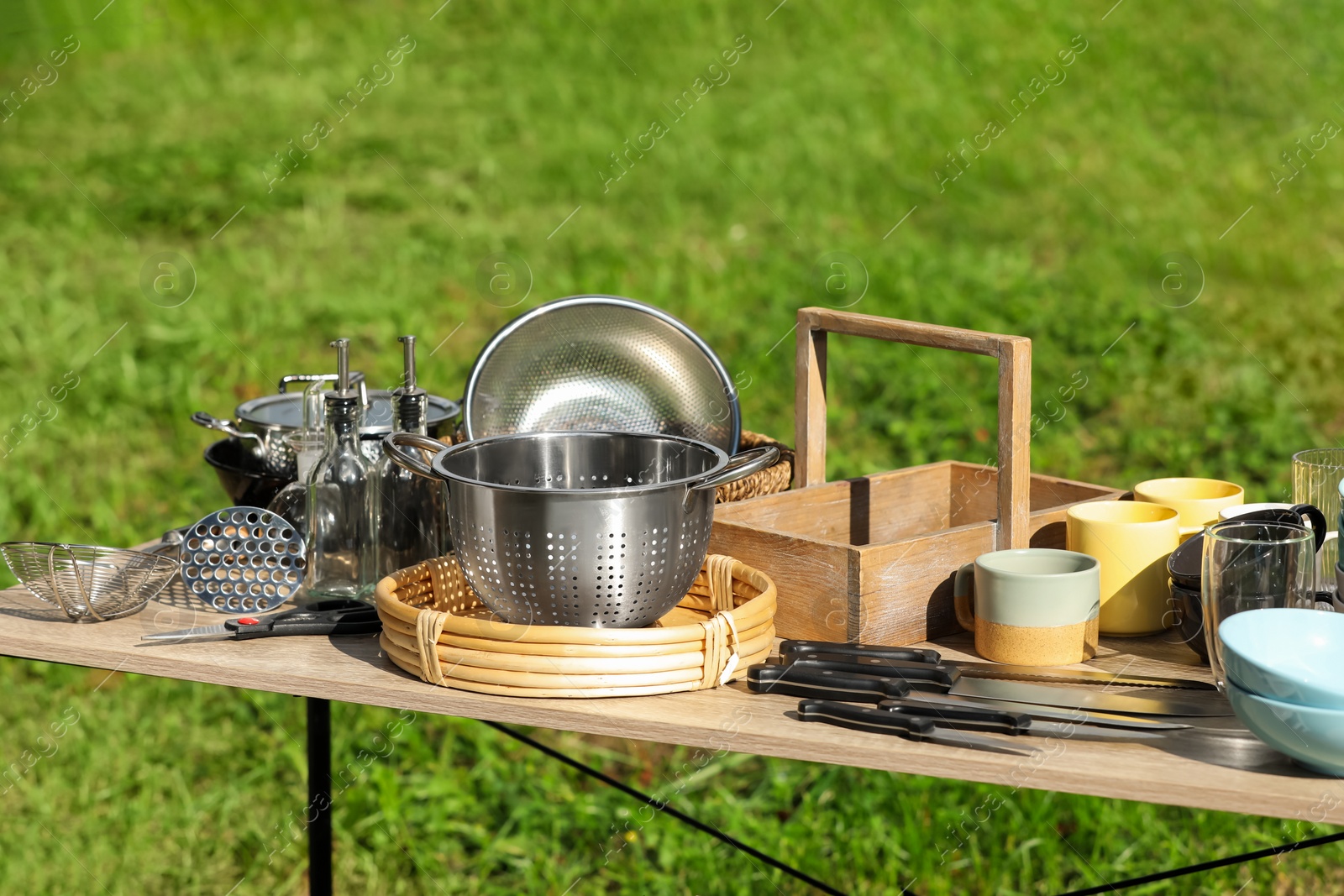 Photo of Many different items for kitchen on wooden table outdoors. Garage sale