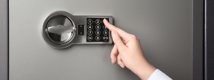Image of Woman opening steel safe with electronic lock, closeup. Banner design
