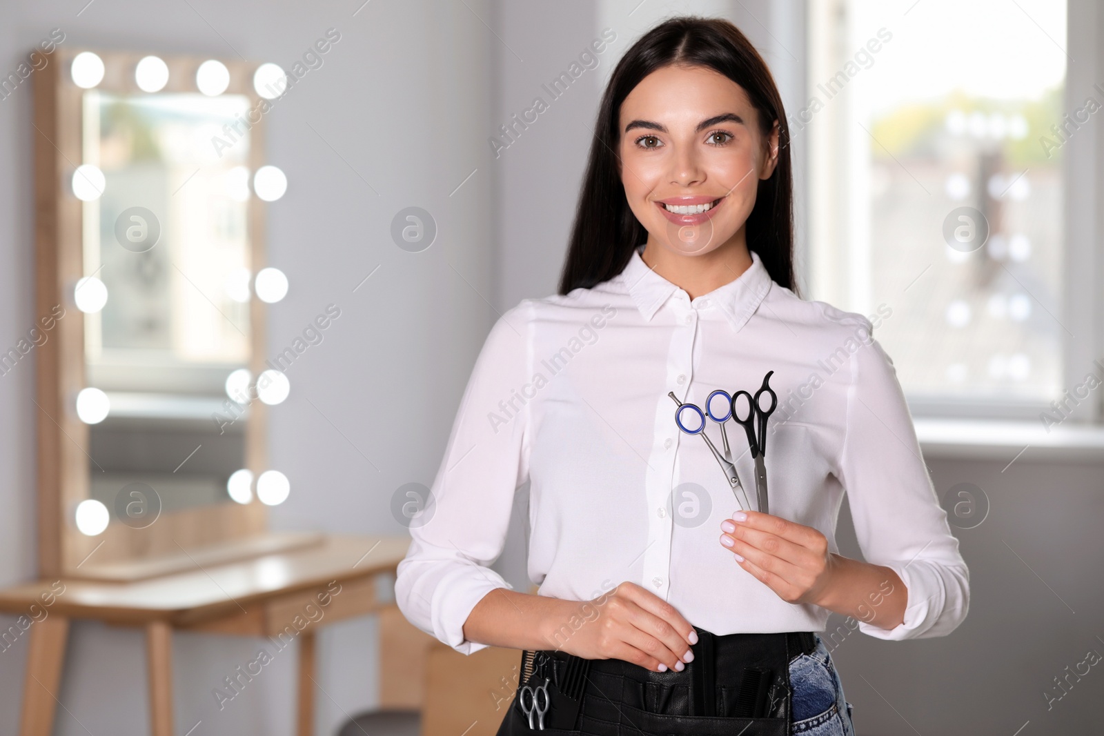 Photo of Portrait of happy hairdresser with professional scissors in beauty salon, space for text