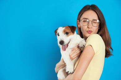 Young woman with her cute Jack Russell Terrier on light blue background. Lovely pet