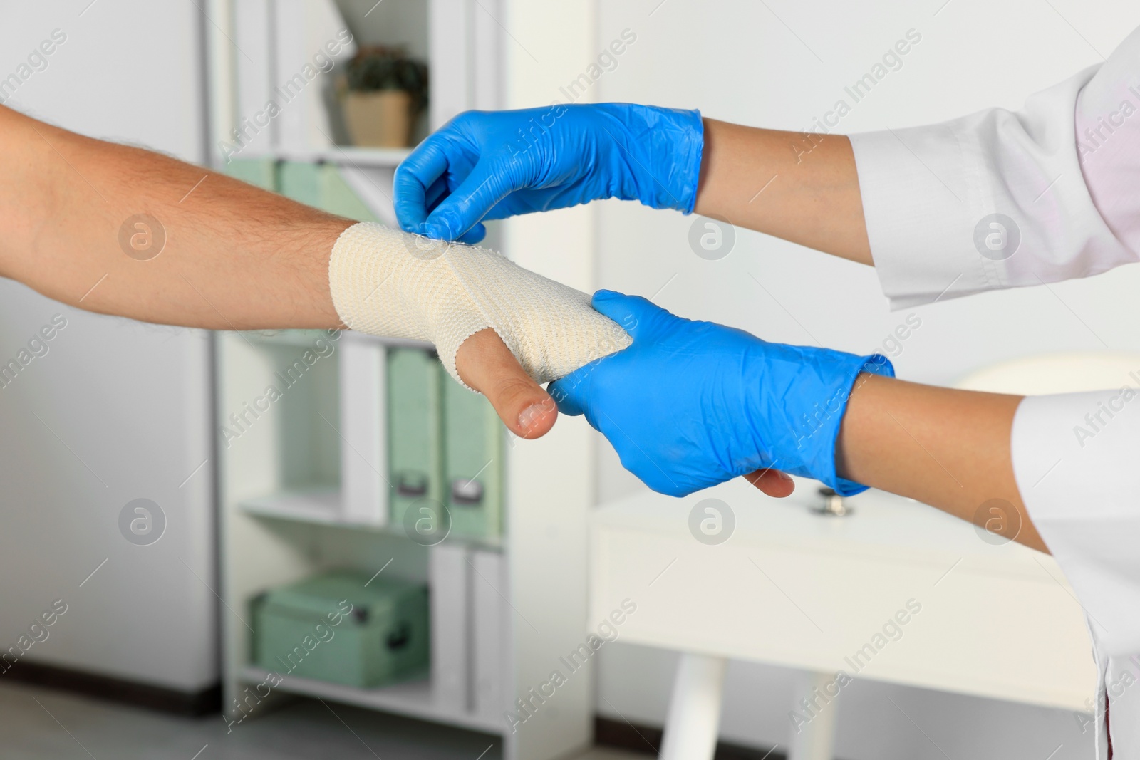 Photo of Doctor applying medical bandage onto patient's hand in hospital, closeup