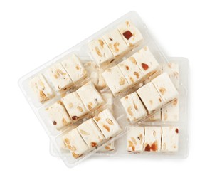 Photo of Plastic containers with pieces of nougat on white background, top view