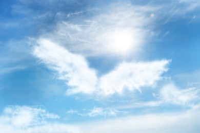 Silhouette of angel's wings made of clouds in blue sky 