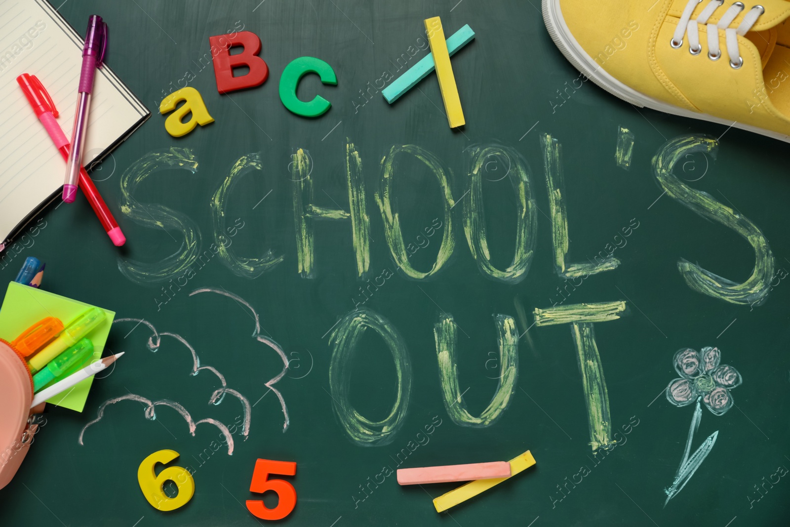 Photo of Pieces of color chalk, shoes and stationery on greenboard with text School's Out, flat lay. Summer holidays