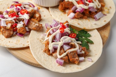 Delicious tacos with vegetables, meat and sauce on white table