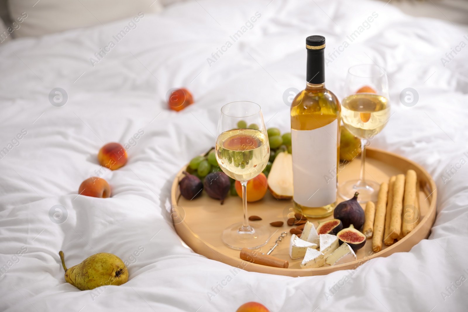 Photo of Different tasty food and wine on white blanket at picnic