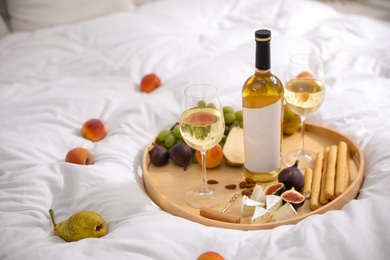 Photo of Different tasty food and wine on white blanket at picnic