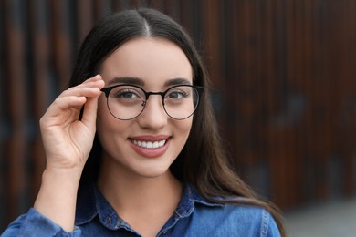 Portrait of beautiful woman in glasses on blurred background. Attractive lady smiling and looking into camera. Space for text