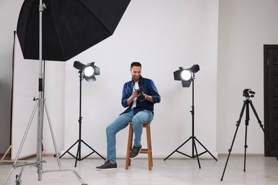 Photo of Young professional photographer with camera in modern photo studio