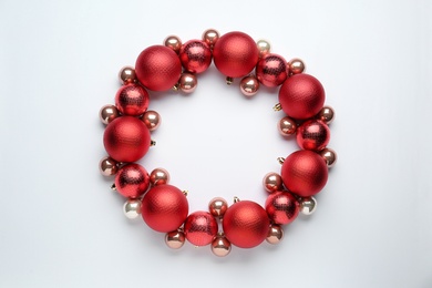 Photo of Beautiful festive wreath made of red Christmas balls on white background, top view