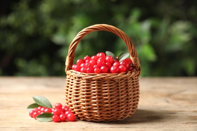 Photo of Ripe fresh cranberry in wicker basket on wooden table