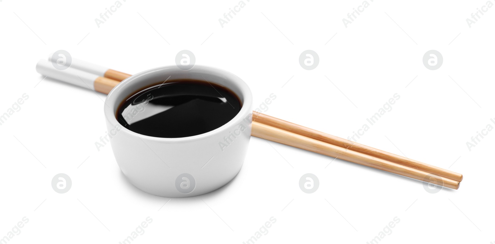 Photo of Soy sauce in bowl and chopsticks on white background
