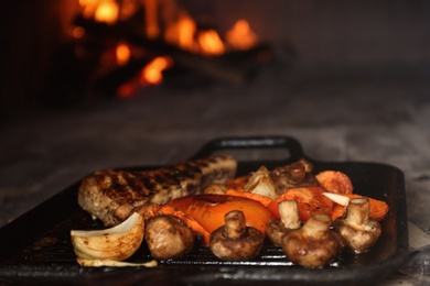 Taking grill pan with meat and garnish out of oven