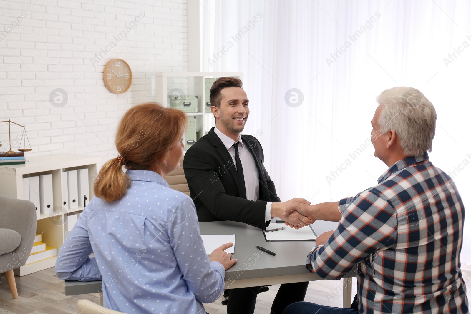 Photo of Young lawyer consulting senior couple in office