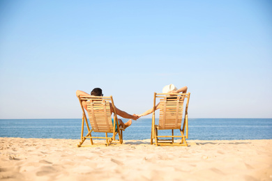 Couple resting on sunny beach at resort