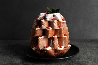 Photo of Delicious Pandoro Christmas tree cake with powdered sugar and berries on black table